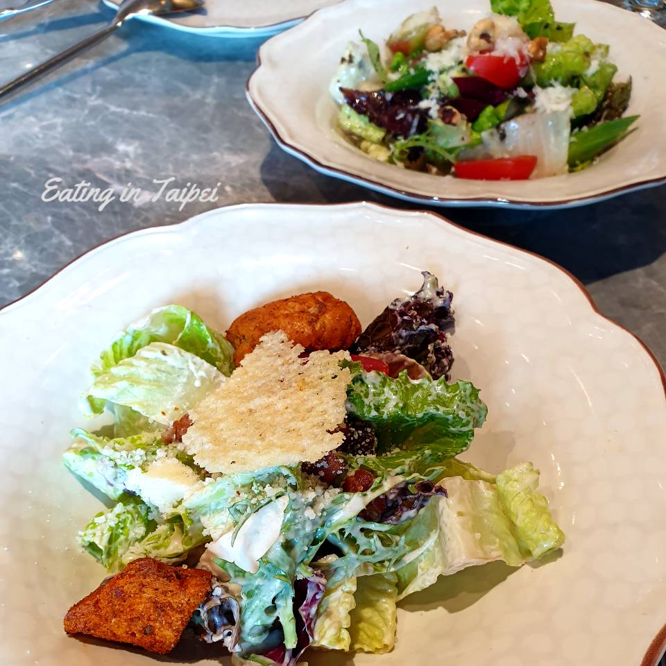 The salad is a mix of crunchy leaves, with some cheese and dressing mixed in there somewhere, too.